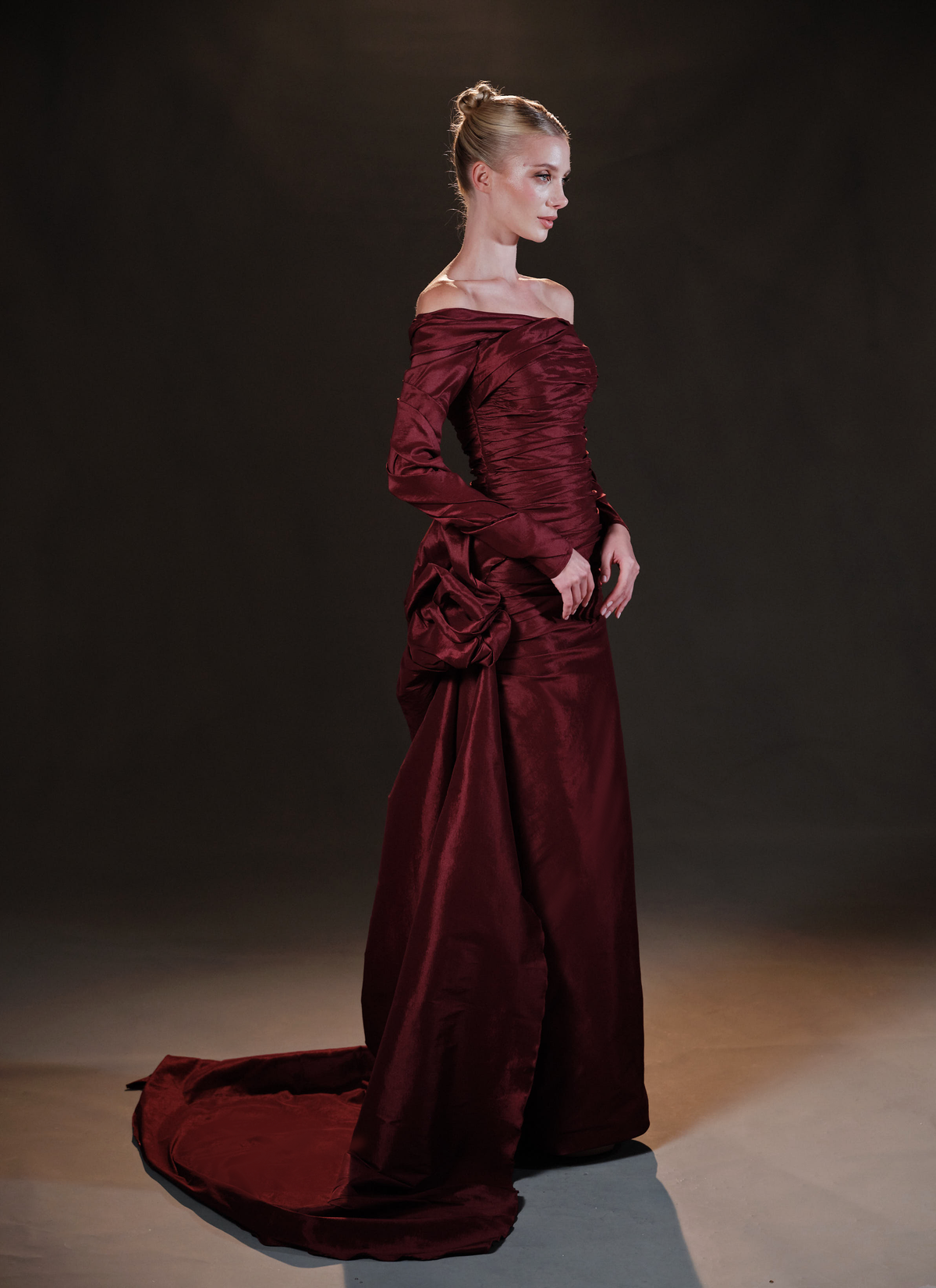 Woman in elegant gold metallic halter gown with dramatic ruffled sleeves on black background