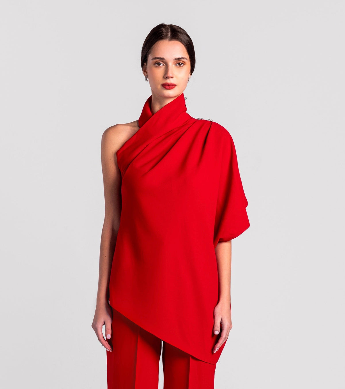 Woman in a red one-shoulder asymmetrical top and matching wide-leg pants.